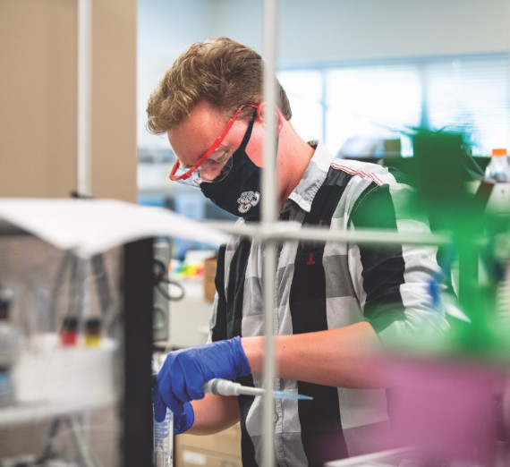 Two people study a plant in a greenhouse.